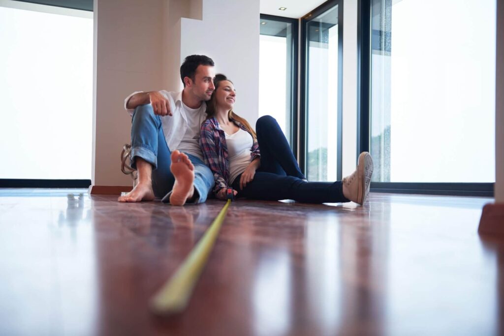 Man and woman sitting on the floor of their home contemplating their renovation options | featured image for the Renovation Options – Exploring Your Choices blog from Renovare.